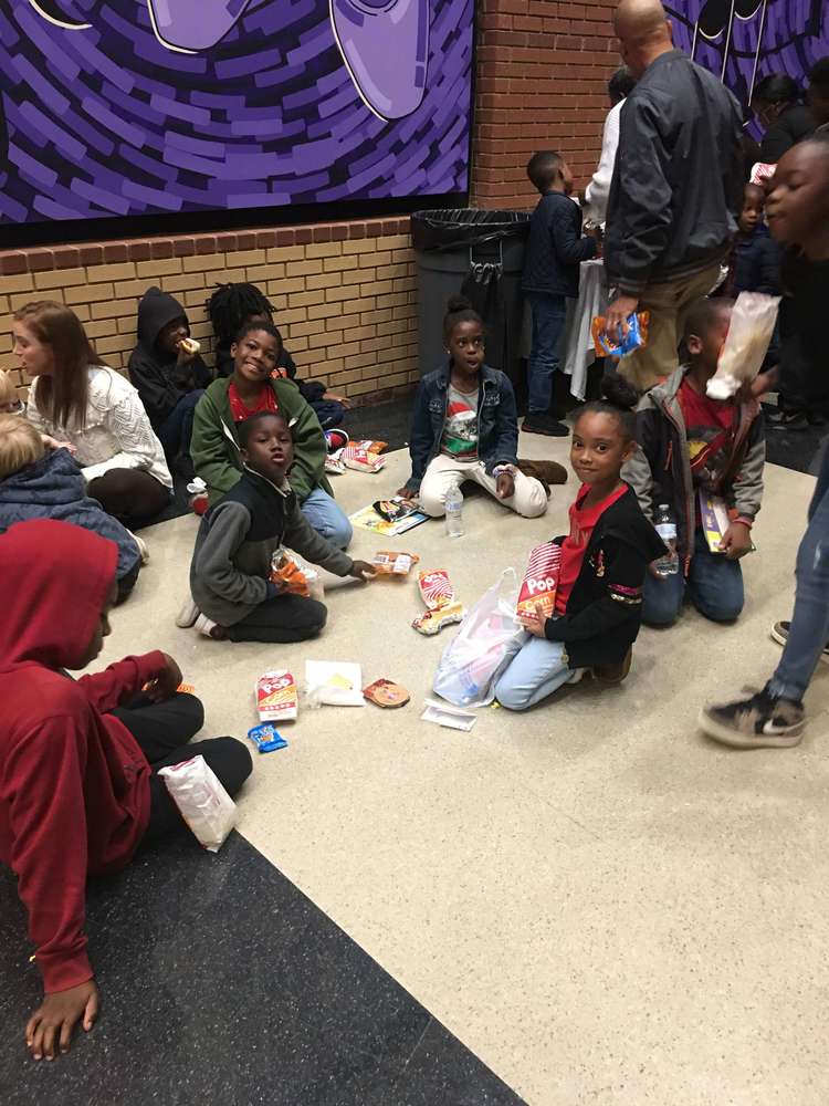 Kids seated on floor eating snacks