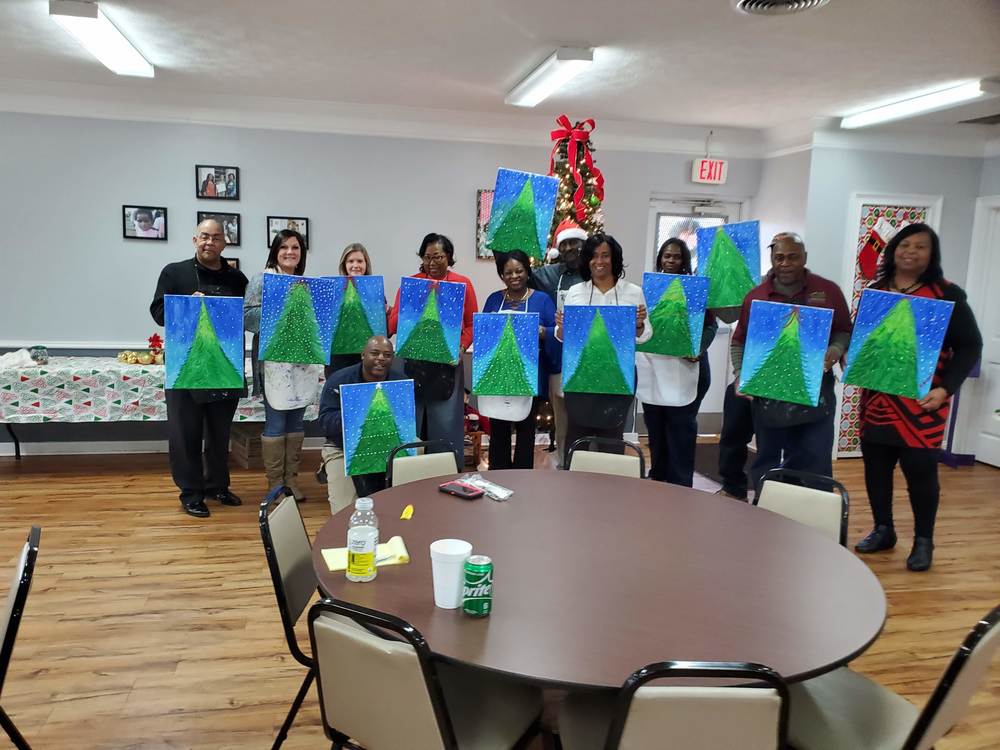Group photo with everyone holding their painting of a Christmas tree