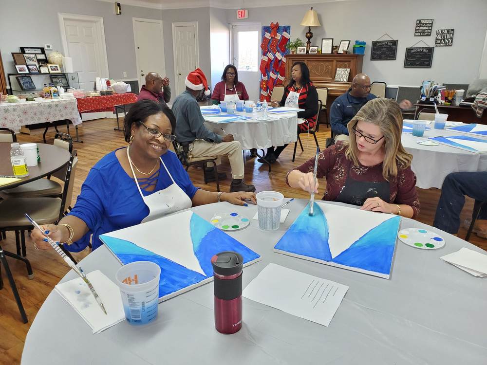 2 staff members starting their painting with blue background