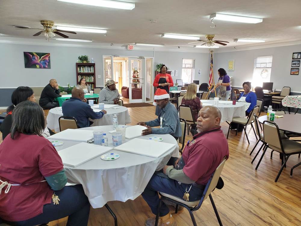 Staff seated at tables waiting for painting activity to begin