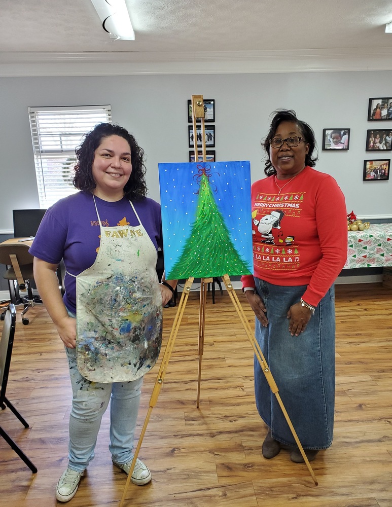 Employee showing their painting on an easel 