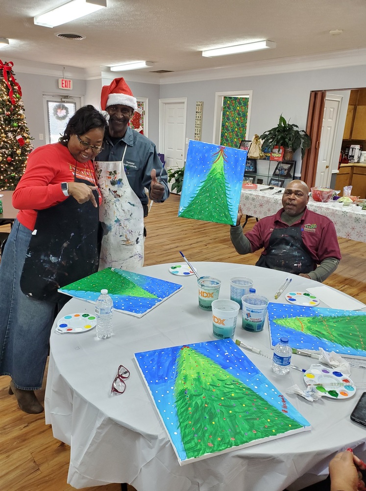 Table at paint party with four employee's paintings