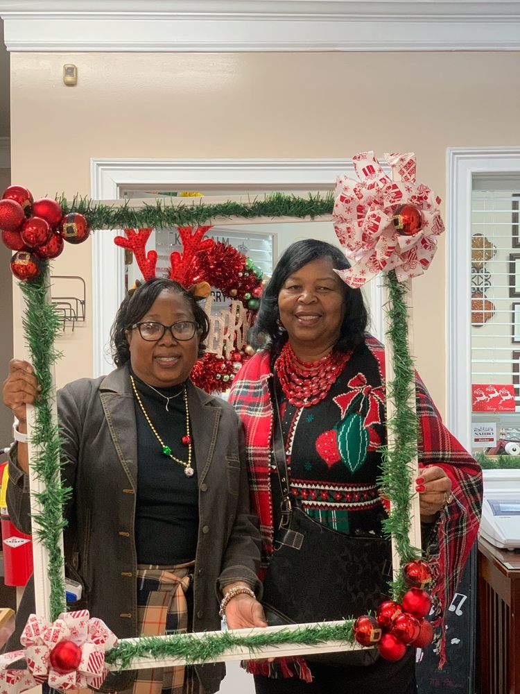 2 women from staff posing with decorative frame