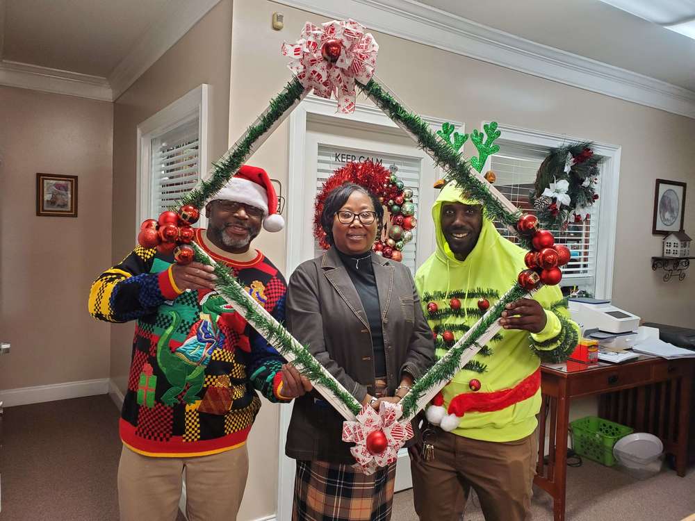 3 staff members holding frame prop for picture