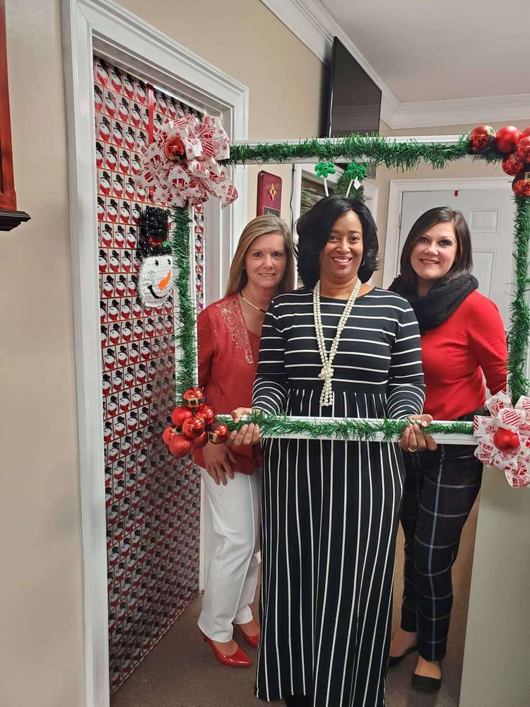 Three women from staff posing with frame prop
