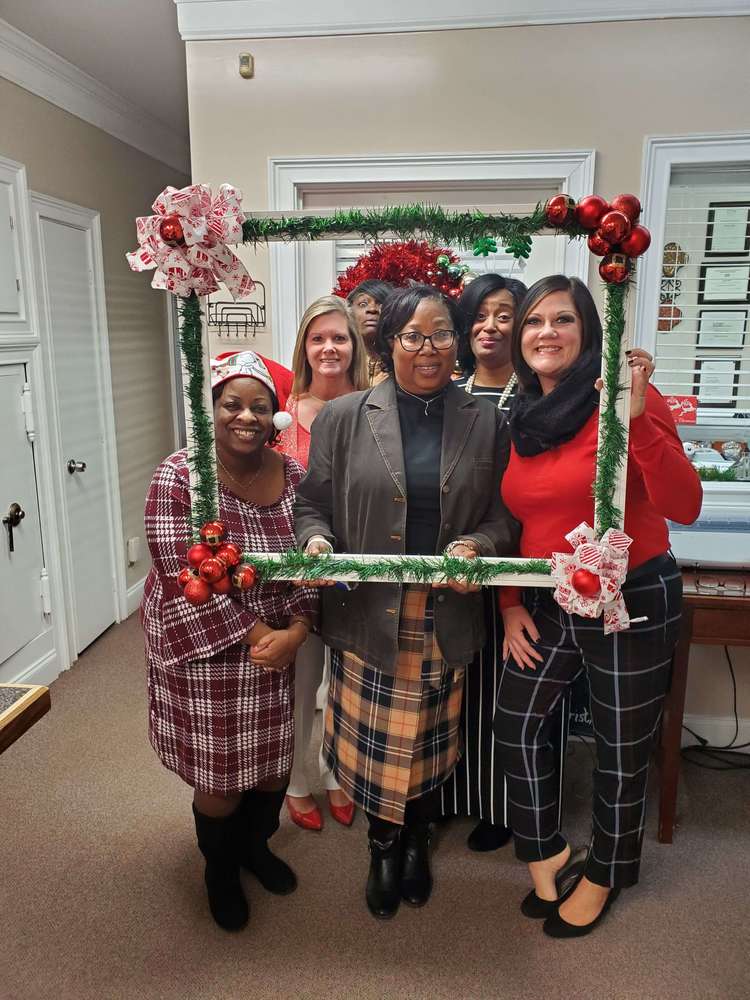 5 women from staff posing with frame prop