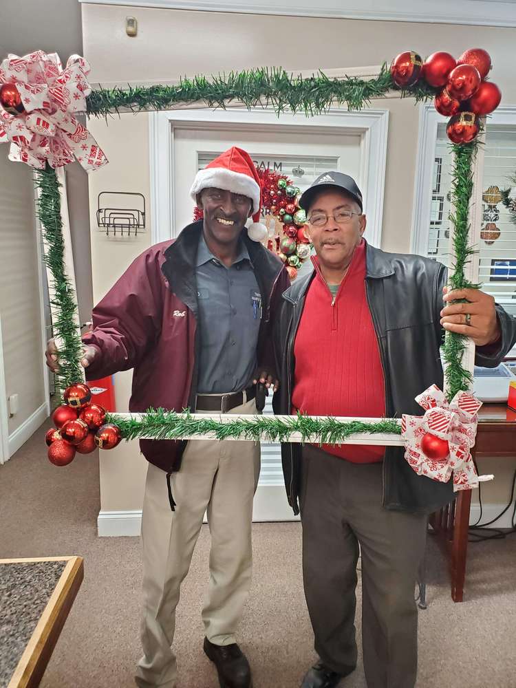 Two men from staff posing holding frame prop