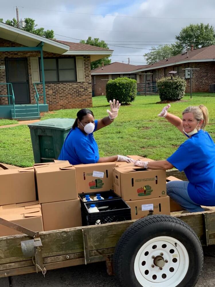 staff members riding trailer with boxes of food