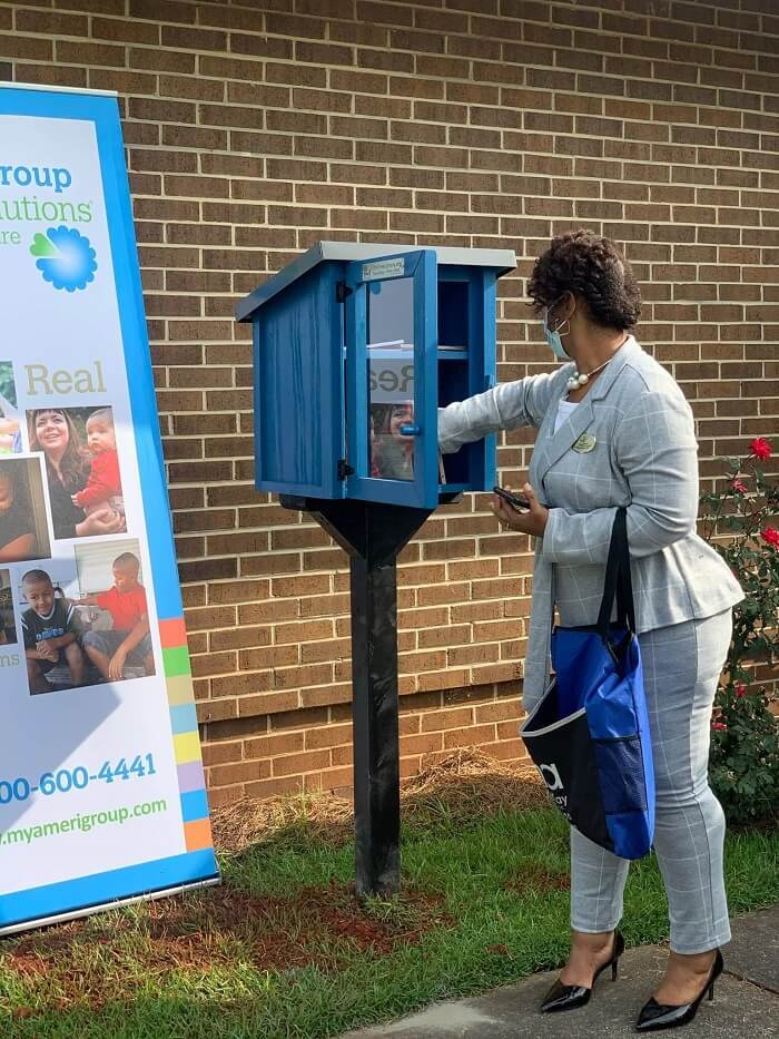 Woman in suit filling little library